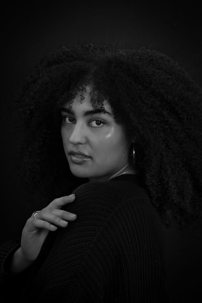 why-choose-us Artistic black and white portrait of a woman with curly hair, expressing elegance and style.